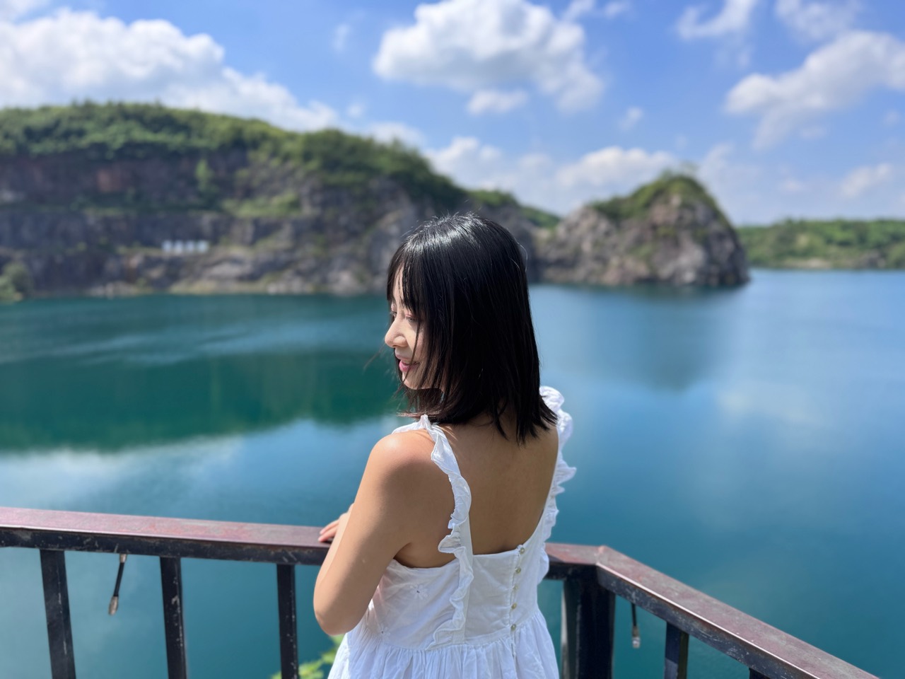 湖畔栏杆旁，穿白色连衣裙的长发女孩回望。